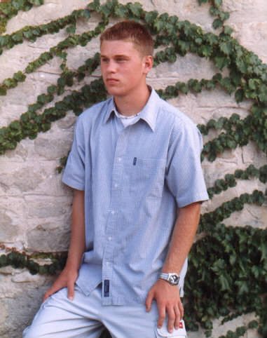 Boy looking away from the camera in front of a stone wall for his yearbook graduation photo