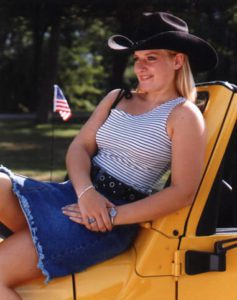Girl outside on yellow jeep for her yearbook graduation portrait