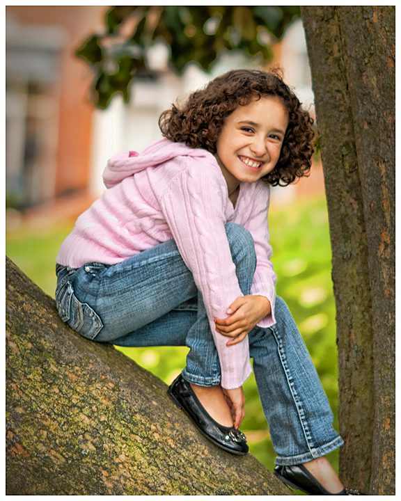 family and children portrait photographer. Little girl portrait sitting in a tree