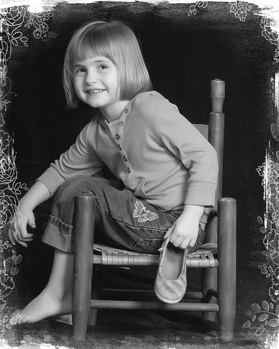 family and children portrait photograper. Little girl sitting in a chair with her shoe off and smiling